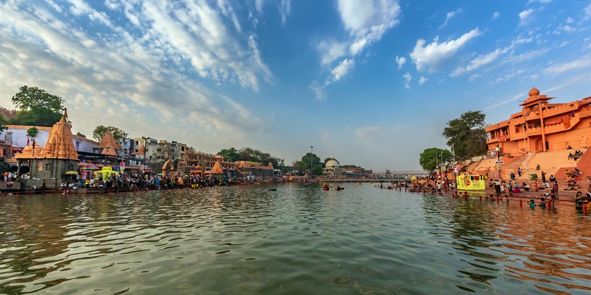 A large number of people, including children, are taking a holy bath in the river Ganges