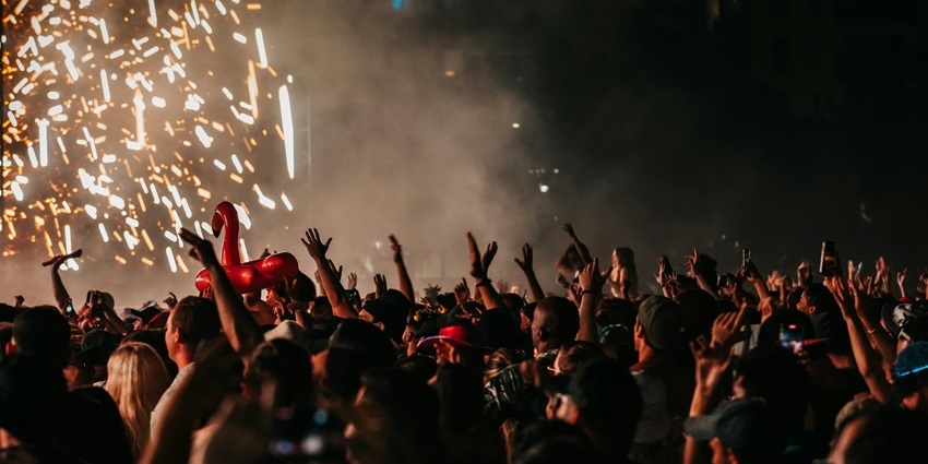 Image of crowd cheering, dancing and enjoying the music festival at night