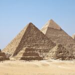 Pyramids of Giza with three tall pyramids and other small ruined pyramids in the desert.