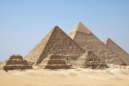 Pyramids of Giza with three tall pyramids and other small ruined pyramids in the desert.