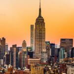 An image of the Empire State Building framed by skyscrapers, seen from Rockefeller Center during sunset.