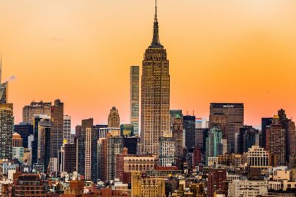 An image of the Empire State Building framed by skyscrapers, seen from Rockefeller Center during sunset.