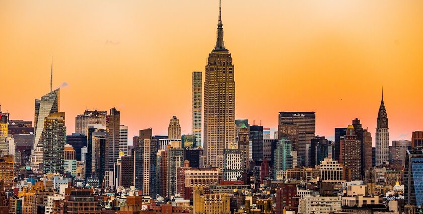 An image of the Empire State Building framed by skyscrapers, seen from Rockefeller Center during sunset.