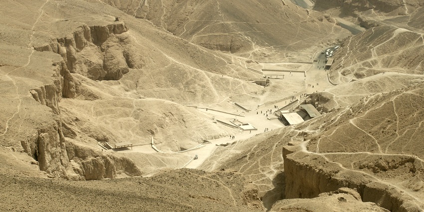 Valley of the Kings from the top with distant people and vehicles in the sandy mountains