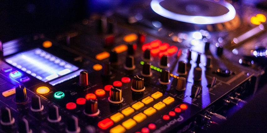 Energetic crowd dancing in a blue-lit nightclub enclosure creates a lively party atmosphere.