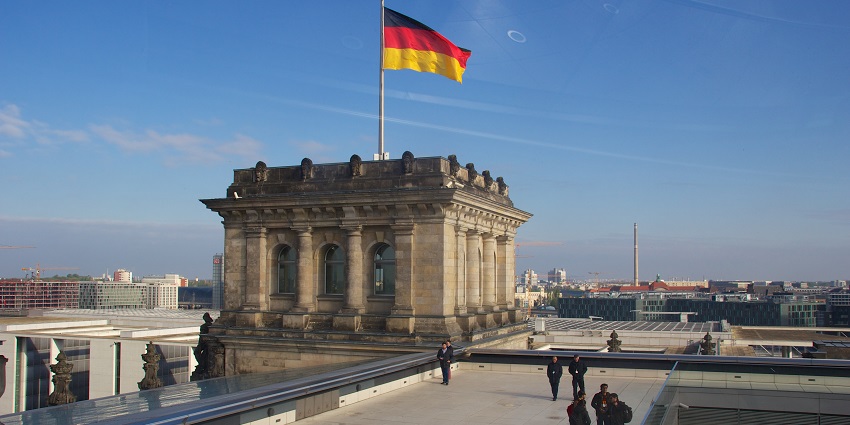 Reichstag dome with people exploring the structure and German flag hosted on the building