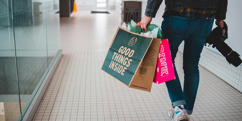 Image of a person carrying shopping bags and a camera inside shopping mall