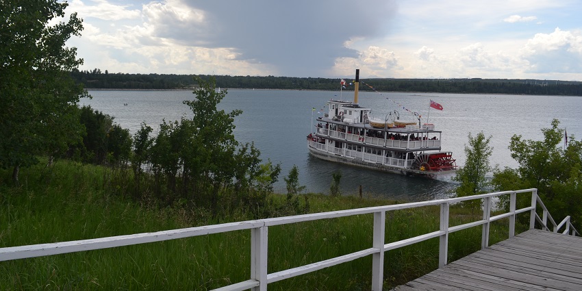 Heritage Park with a wooden bay, a cruise yacht full of people in the Glenmore reservoir