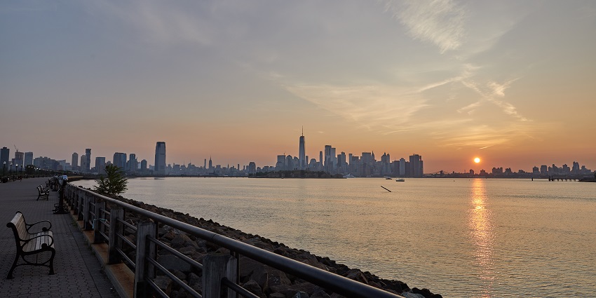 Liberty State Park with the Hudson River and people sitting on the benches during sunrise