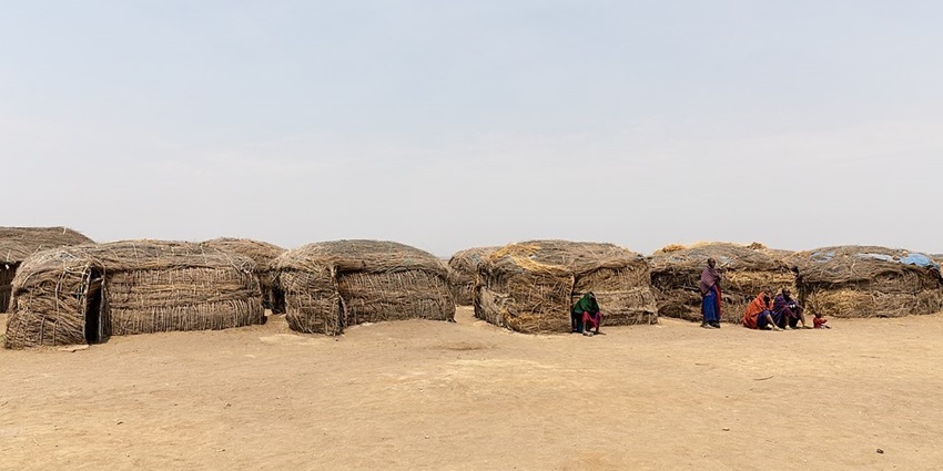 Masai village with traditional houses made up of grass and mud and people sitting