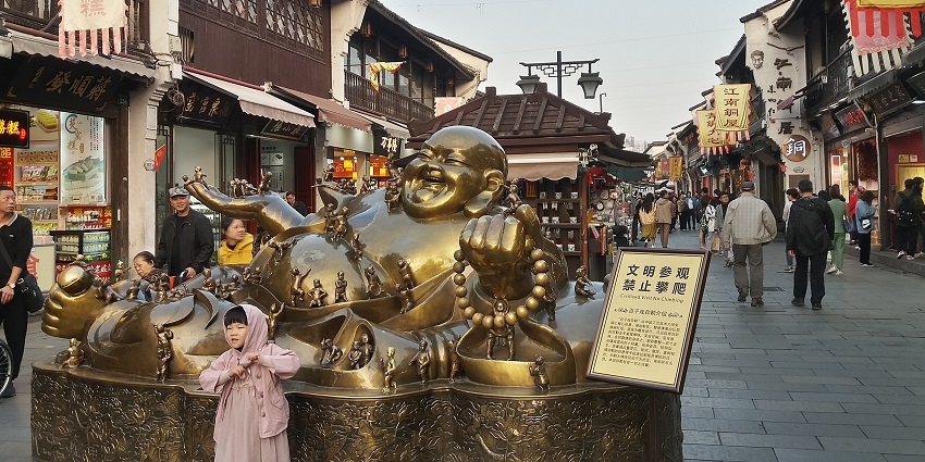 Image of Laughing Buddha statue in Hefang Street, bustling market around