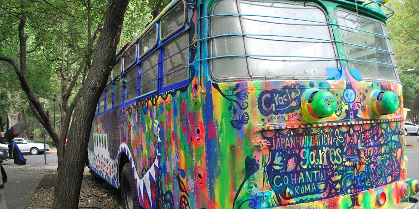 A bus coloured with vibrant graffiti stands by a road in Condesa, Mexico City, Mexico.