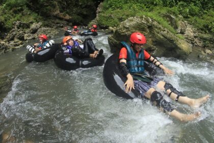 A picture of a group of people enjoying river rafting in a lush green environment.