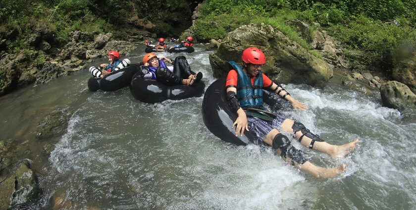 A picture of a group of people enjoying river rafting in a lush green environment.