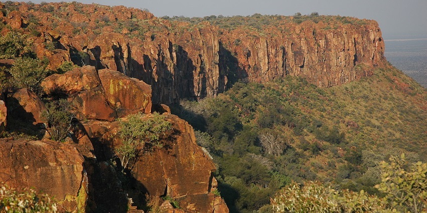 A view of the Namibian Waterberg Plateau surrounded by huge rocks, bushes and sky in background