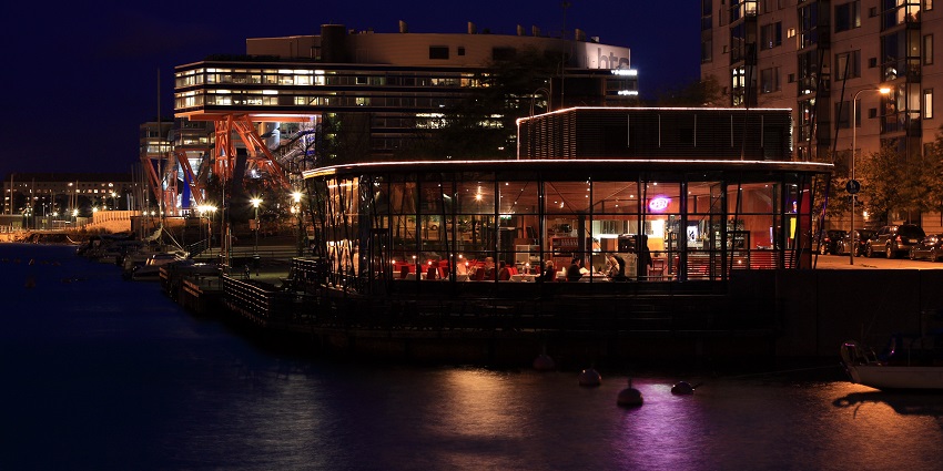 Night view of a restaurant in Finland filled with customers enjoying their food.