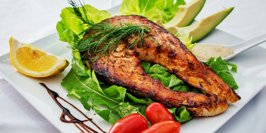 Image of a seafood plate served a grilled fish with fried veggies on a white plate