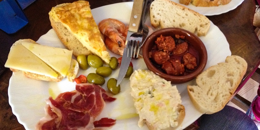 Image of a delicious platter of Spanish Tapas served on a table and a drink on the side