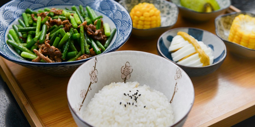 Image of Rice on Bowl, Sliced-egg, Corn, and Vegetable on Table