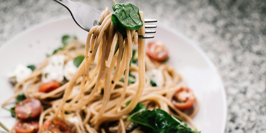 An image of a delicious plate of spaghetti with tomatoes, fresh basil, and mozzarella cheese.
