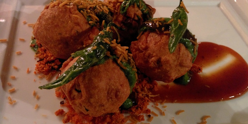 Image of Vada pav served on a plate with delectable platter and a fried chilli on top