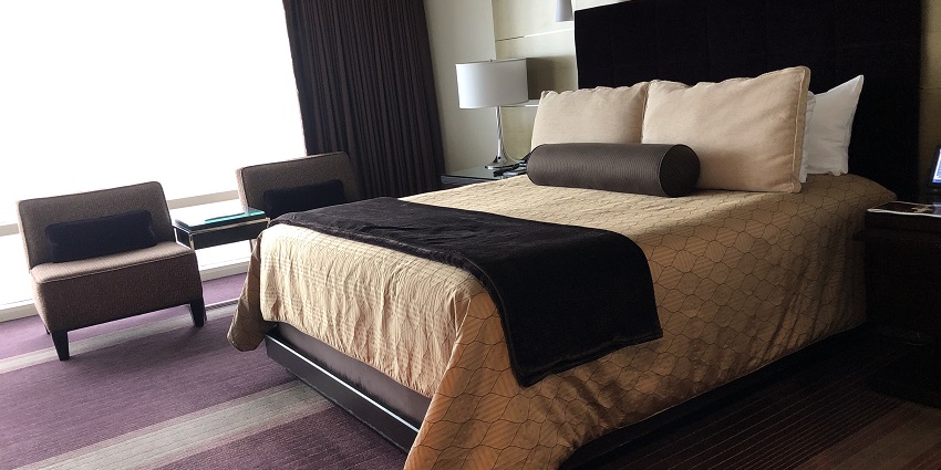 A lavish executive suite room with a view of a river from a glass window.