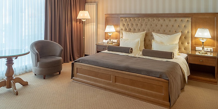 A lavish executive suite room with a view of a river from a glass window.