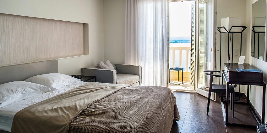 Image of a hotel room with a black Wooden Table Near Wall and a sofa on the side with a balcony in front