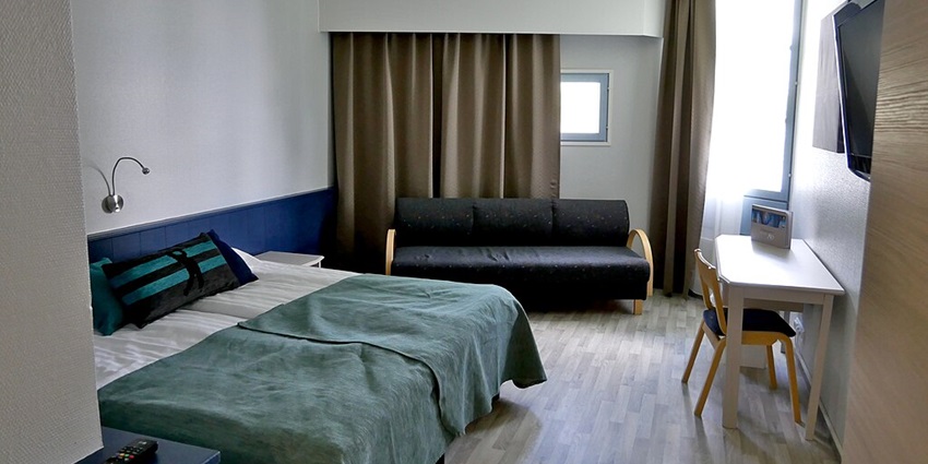 An inner view of a hotel room that has a twin bed and a television with other amenities.