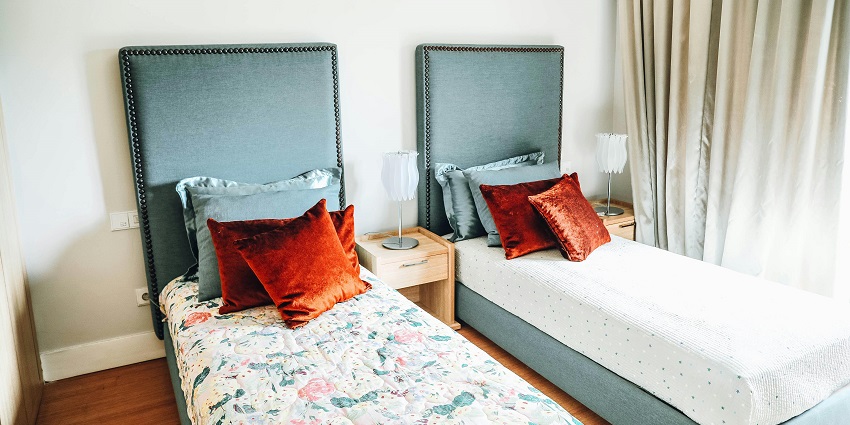 An image of a hotel room with two separate beds with comfortable pillows and clean sheets