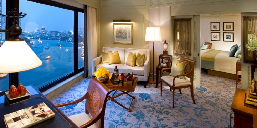 A lavish executive suite room with a view of a river from a glass window
