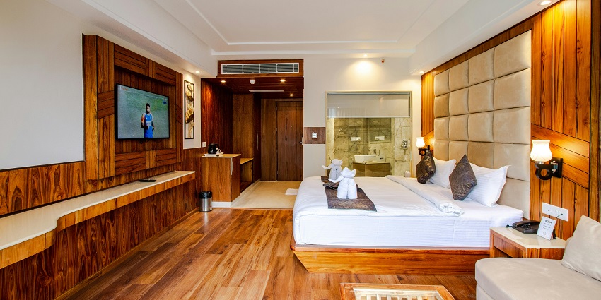 Image of a hotel room inside with comfortable bed and a sofa on the side also a TV