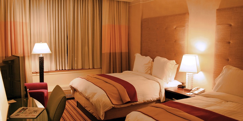 A lavish executive suite room with a view of a river from a glass window.
