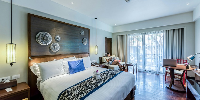View of the beautiful interior of a hotel room with a traveller relaxing on the couch.