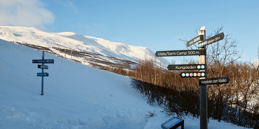 Kings Trail in Abisko National Park is covered in snow with directional signboards.