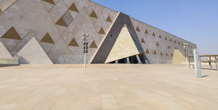 An outer structure of the Grand Egyptian Museum can be seen, covered in triangle glass.