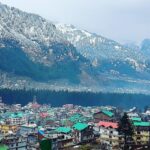 Beautiful snow sprinkled trees on the hills with vibrant houses in the foreground in Manali, Himachal Pradesh.