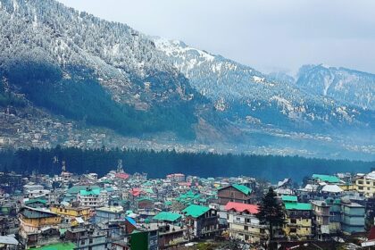 Beautiful snow sprinkled trees on the hills with vibrant houses in the foreground in Manali, Himachal Pradesh.