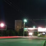 Lit street lamps at the side of the road at night in Chisinau with billboards and buildings