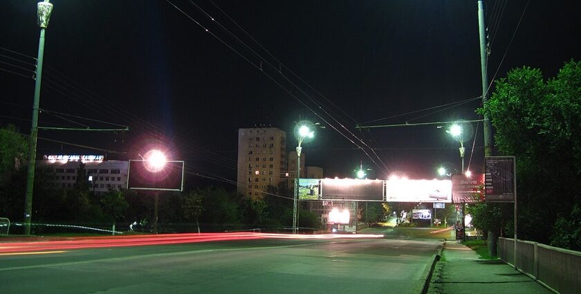 Lit street lamps at the side of the road at night in Chisinau with billboards and buildings