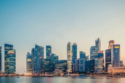 The official mascot of Singapore, is a lion, with tall skyscrapers in the background.