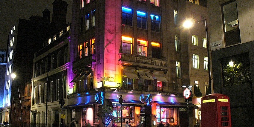 An image showing Soho at night, illuminated by vibrant lights and bustling activity.