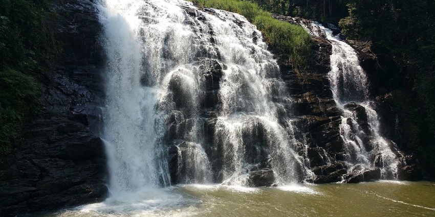 Abbey Falls, with water cascading down the rocks surrounded by greenery in Coorg.