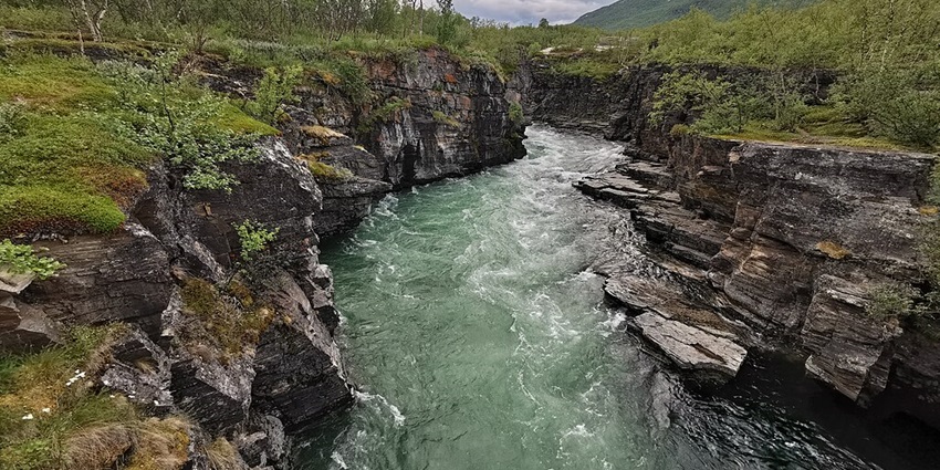 An image showing Abiskojåkka river in Abisko National Park, surrounded by pristine nature.