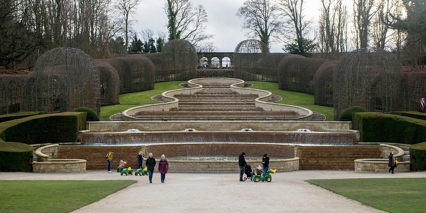 An image showing the stunning cascade at Alnwick Garden, surrounded by lush greenery.