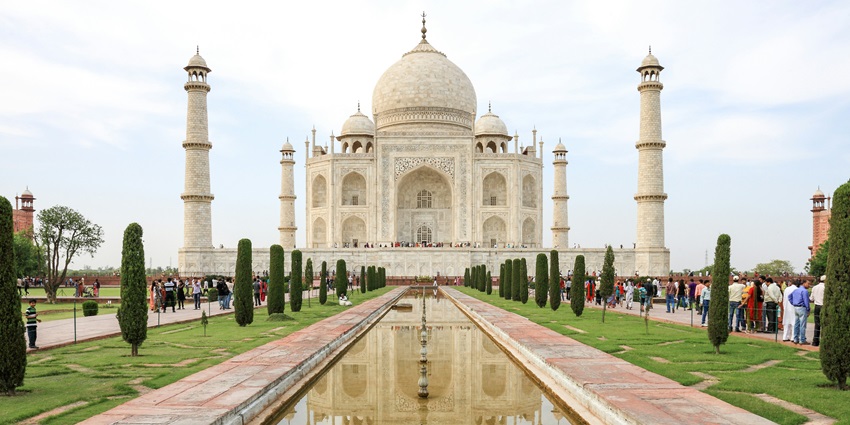 An image of the Taj Mahal at sunrise, with the monument reflecting in the calm Yamuna River.