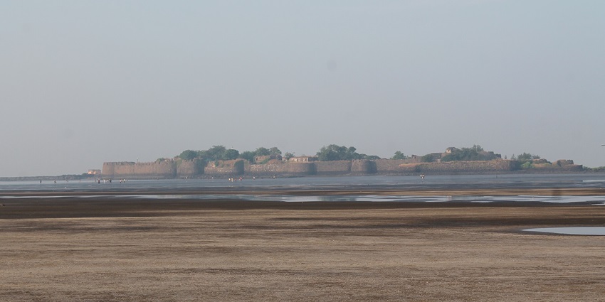 An image of the Kolaba fort surrounded by water with people walking along the perimeter.