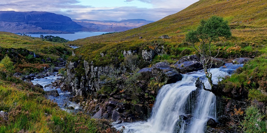 Waterfall flowing over rocks, surrounded by greenery similar to Allt Nan Uamh Waterfall