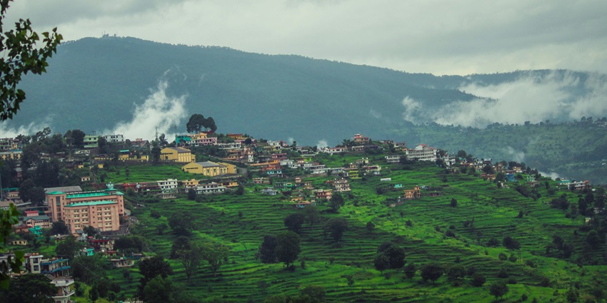 A panoramic view of Almora with terraced hills and traditional Kumaoni homes.
