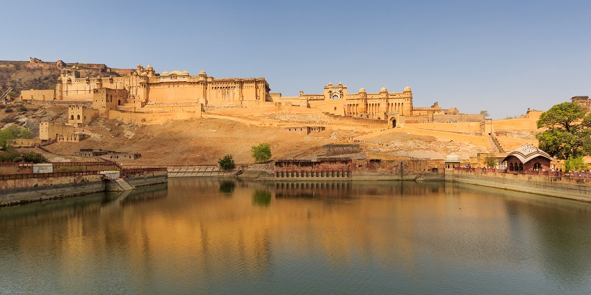 An image of Amer Fort in Jaipur, India, reflected in Maota Lake under a clear sky.